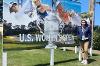 Lizzie Crawford, wearing her credentials, stands in front of a banner for the U.S. Women's Open Golf Tournament.